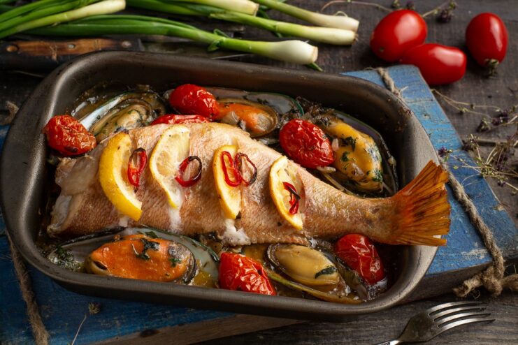 A plate of cooked Provençal-style sea bass with mussels, garnished with herbs.