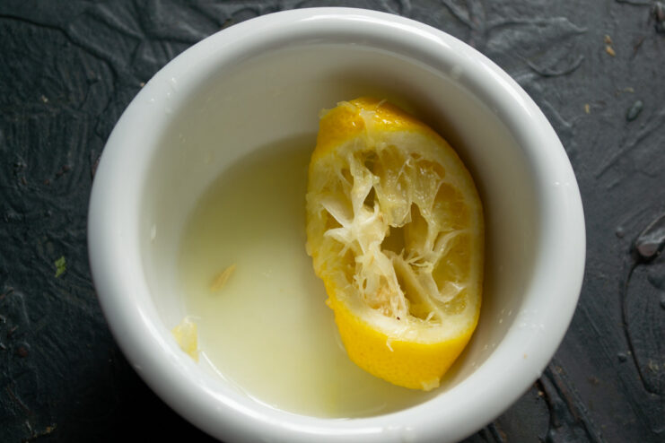 Squeezing Lemon Juice — Freshly squeezed lemon juice works best as a natural coagulant. A hand squeezing a lemon slice to extract fresh juice into a small bowl.