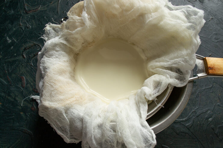 Straining the Curds — Pour the mixture carefully to separate the curds from the whey. Pouring the curdled milk and smetana mixture into a colander lined with cheesecloth.