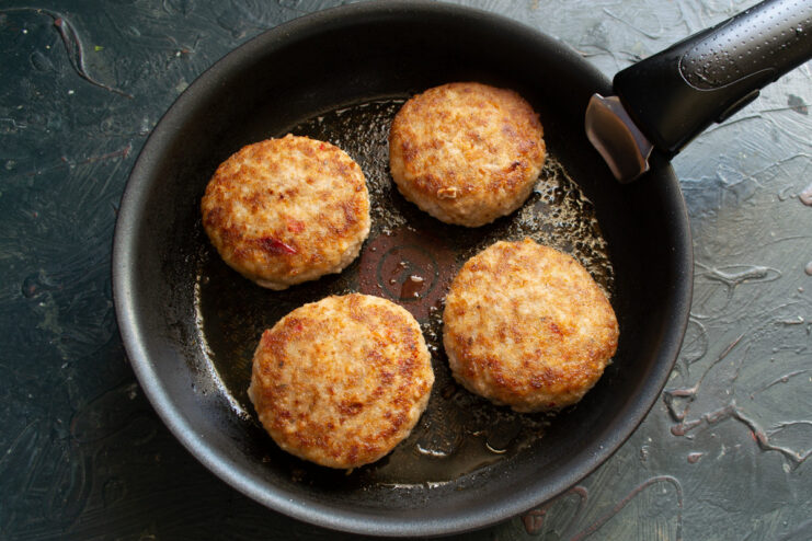 Flipping the Patties to Cook the Other Side Flipping the meat patties in the frying pan to cook the second side.