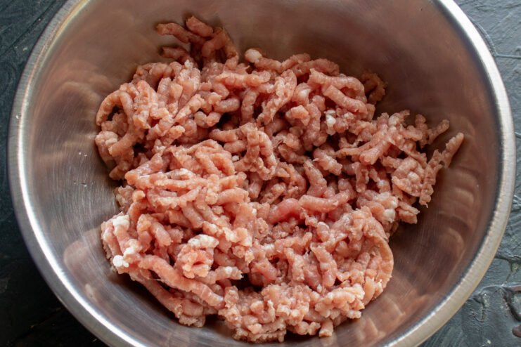 Grinding Lean Meat for the Patties Close-up of lean meat being processed through a meat grinder.
