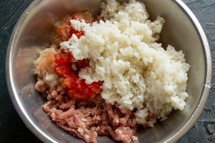 Combining Cooked Rice with Ground Meat A bowl of ground meat mixture with cooked rice being added to it.