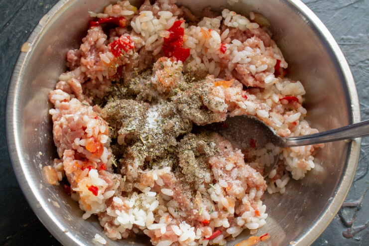 Seasoning the Meat and Rice Mixture Seasoning being added to the bowl of ground meat and rice mixture.