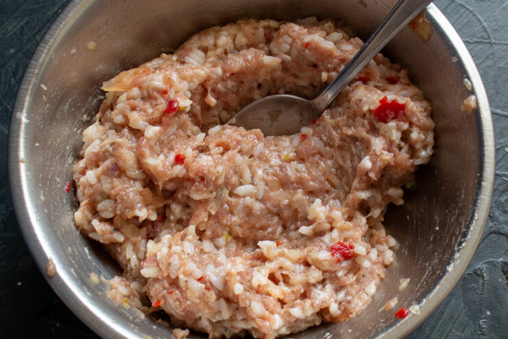 Mixing the Patty Ingredients Thoroughly Hands thoroughly mixing the ground meat, rice, and seasonings in a bowl.