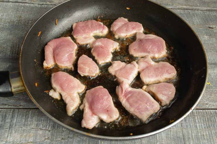 Searing the Pork Slices Until Golden Brown Pork slices searing in a hot skillet until golden brown.