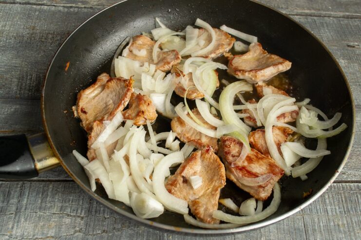 Adding Garlic and Onions to the Seared Pork Minced garlic and sliced onions being added to the skillet with seared pork.