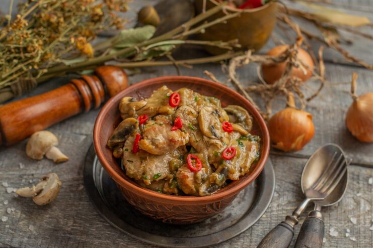 Serving the Hearty Meat and Mushroom Stew A serving of hot meat and mushroom stew in a bowl, ready to be eaten with a side dish.