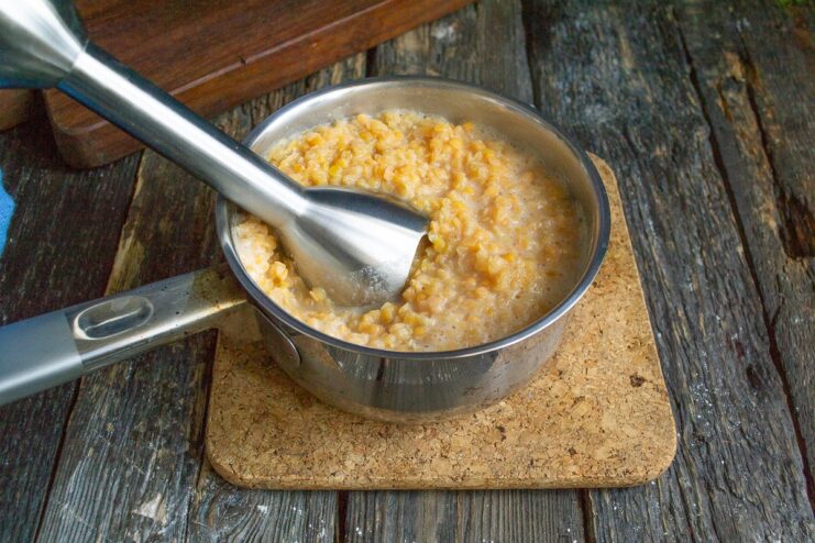 Cooking and Blending the Lentils for Texture Cooked red lentils in a saucepan being blended with an immersion blender.