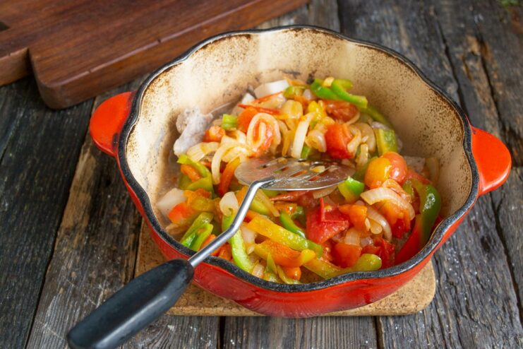 Adding the Sautéed Vegetables to the Pot with the Pork Sautéed vegetables being added to the pot of cooked pork.