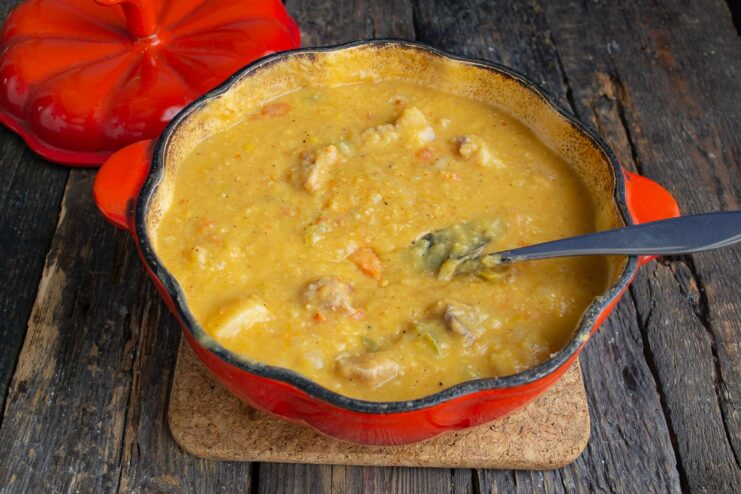Combining All Ingredients and Simmering to Finish Lentil puree and spices being added to the pork and vegetable stew in a pot.