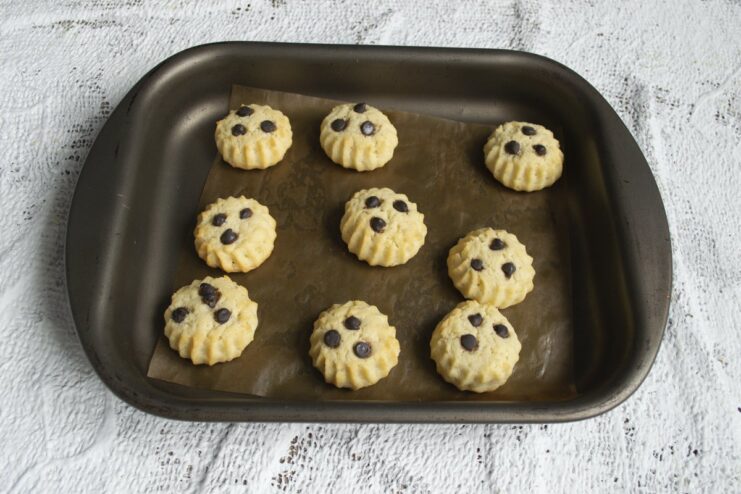 Baking the cookies until they are lightly golden for the perfect crumbly texture. A baking sheet with mayonnaise shortbread cookies baking inside a hot oven.