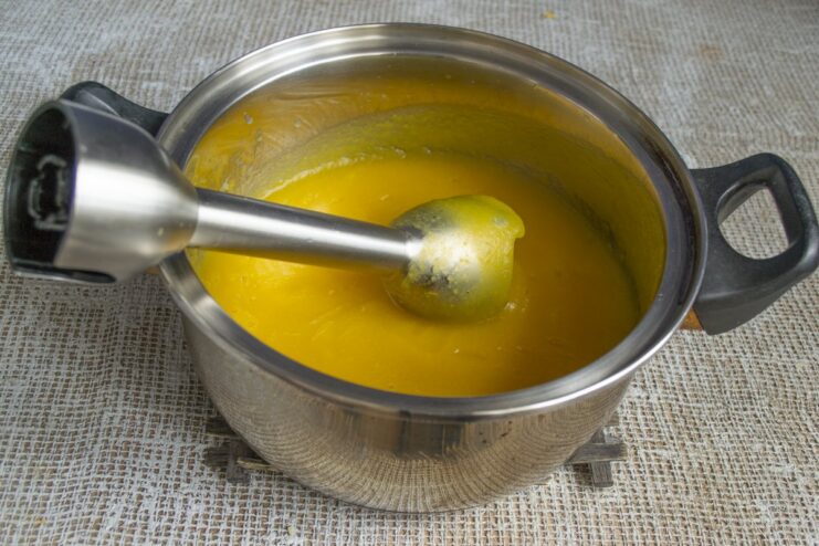 Seasoning the purée and cooking it briefly to meld the flavors. Adding sugar and salt to the smooth pumpkin purée in the pot.