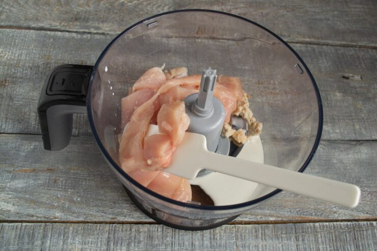 Adding Chicken Fillet to the Blender for Grinding Cubes of raw chicken fillet being added to the blender bowl.