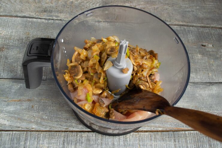 Combining All Ingredients in the Blender for the Kotlety Mixture Adding the cooled mushroom and onion mixture to the chicken in the blender.