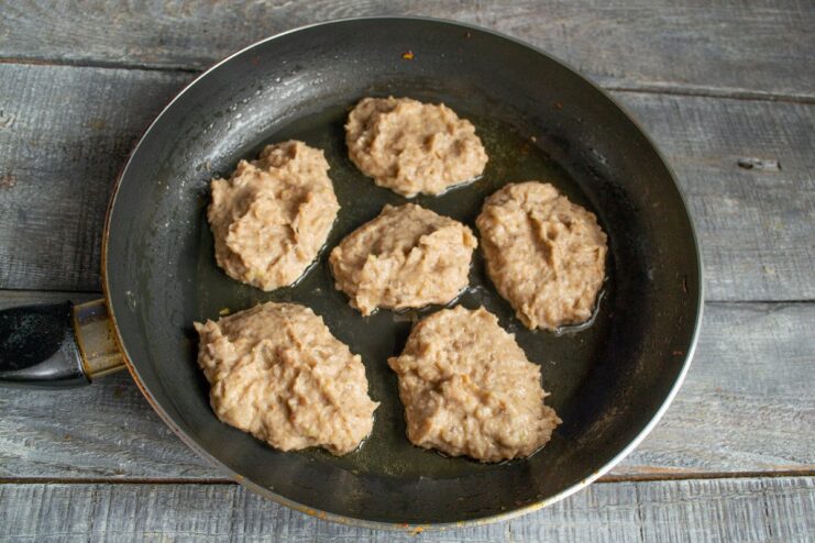 Forming and Frying the Kotlety - Spooning the Mixture into the Pan Spoonfuls of the chicken mixture being placed into a hot frying pan with oil.