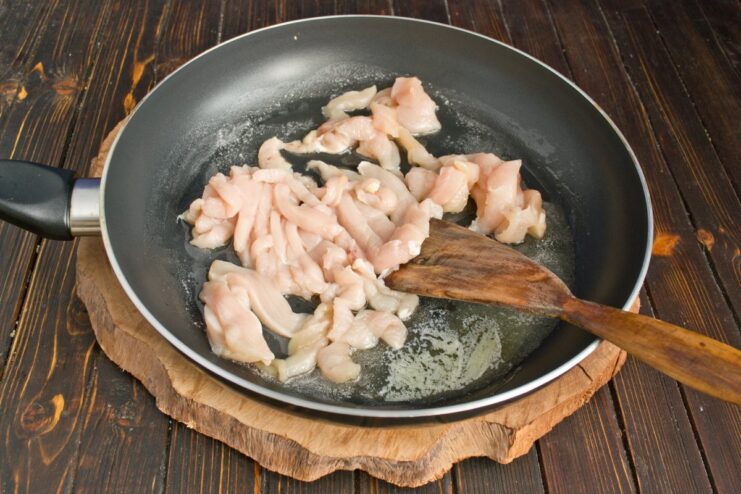 Sautéing Chicken Strips for Pasta Sauce Strips of chicken fillet being sautéed in a hot frying pan until lightly browned.