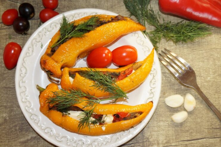 A dish of baked peppers stuffed with mushrooms and feta cheese, ready to be served.