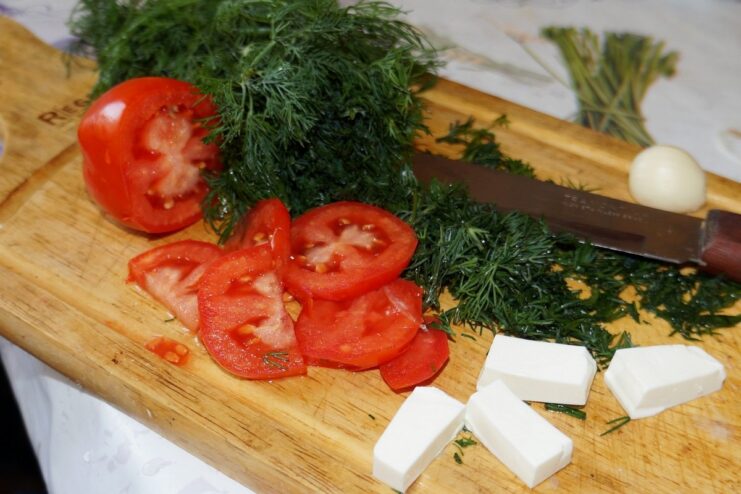 A cutting board with chopped tomatoes, feta cheese, garlic, and herbs for the stuffing.