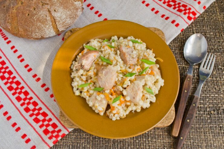 The finished Belarusian-style pearl barley pilaf, ready to be served A close-up of the cooked pearl barley porridge with meat in the pot.