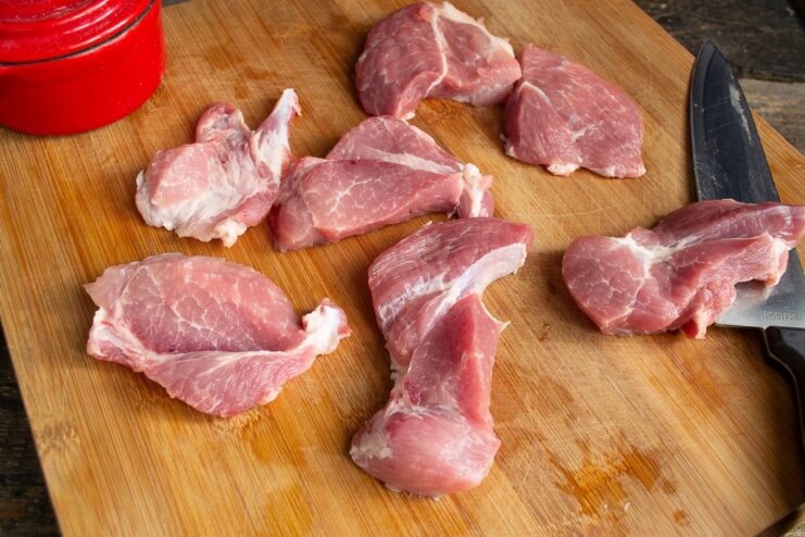Step 1: Slicing and Patting Dry the Pork Raw pork slices on a cutting board being patted dry with a white paper towel.
