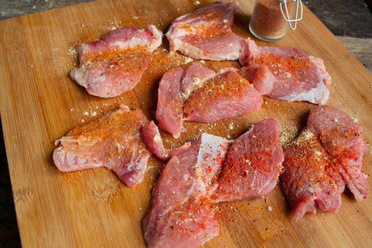 Step 3: Seasoning the Pork Seasoned pork cutlets in a bowl, being mixed with olive oil and spices.