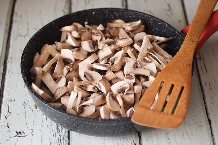 Frying the Mushrooms - Sauté the mushrooms on high heat until golden brown. Sliced mushrooms being sautéed in a hot frying pan with melted butter.