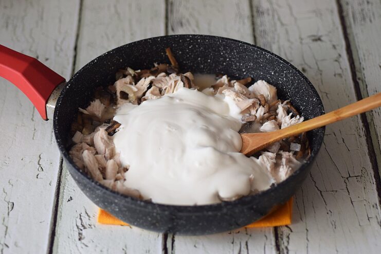 Creating the Creamy Sauce - Pour in the flour-water mixture and smetana to make the gravy. Adding a creamy mixture of smetana and flour slurry to the chicken and mushrooms in the pan.