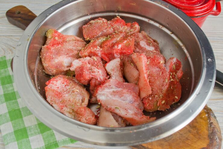 Generously coat each pork slice with the spice rub. Hands rubbing a spice mixture onto raw pork slices.