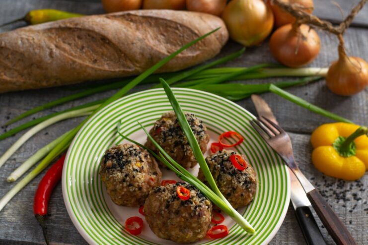 A plate of healthy steamed minced meat tefteli, garnished with fresh herbs and chili.