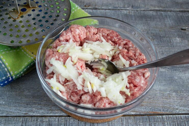 Adding Finely Chopped Onion for Flavor Finely chopped onion being added to a bowl of minced meat.