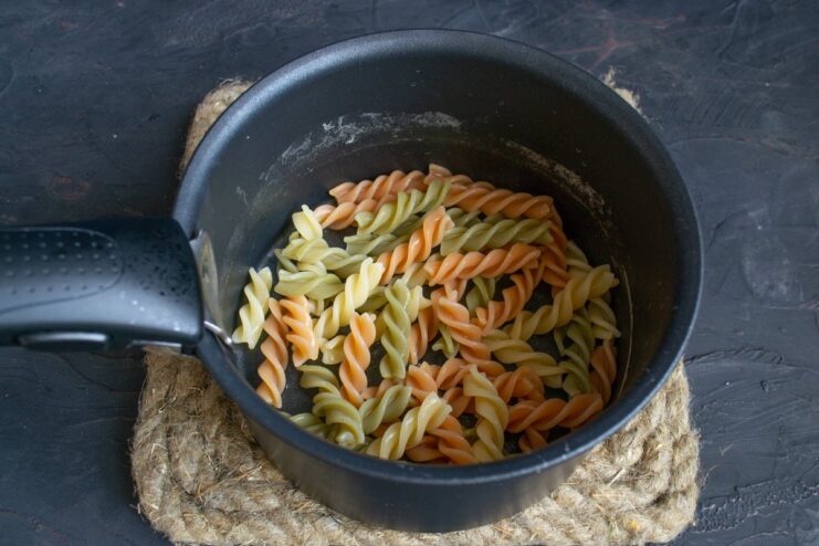 Any type of pasta works well for Koshari Colorful fusilli pasta being boiled in a pot of water.
