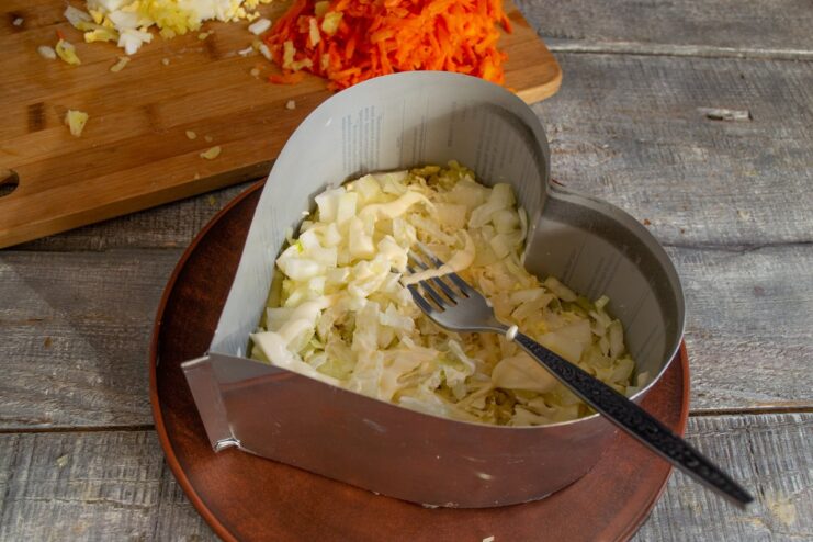 Step 3: Adding the Chopped Onion Layer Chopped onions being spread evenly over the potato and mayonnaise layer in the salad.