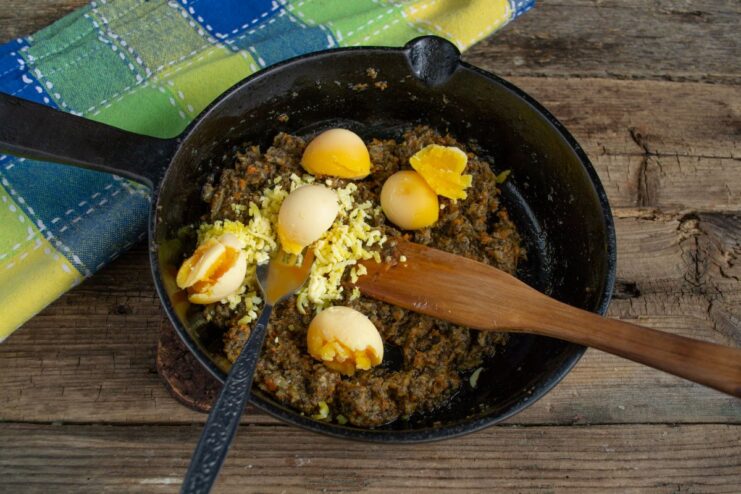 Mixing Egg Yolks with Mushroom Pâté for the Filling Mashed egg yolks being added to the warm mushroom pâté in a skillet.