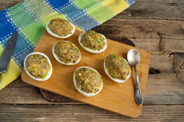 Stuffing Egg Whites with the Mushroom Pâté Filling A hand filling an egg white half with a generous amount of the mushroom and yolk mixture.