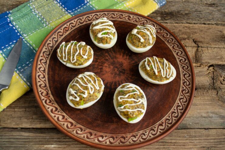 Garnishing Stuffed Eggs with a Drizzle of Mayonnaise Piping a decorative swirl of mayonnaise on top of the filled deviled eggs.
