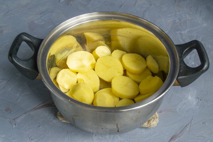 Step 1: Preparing the potatoes for boiling Peeled and sliced raw potatoes in a stainless steel pot.