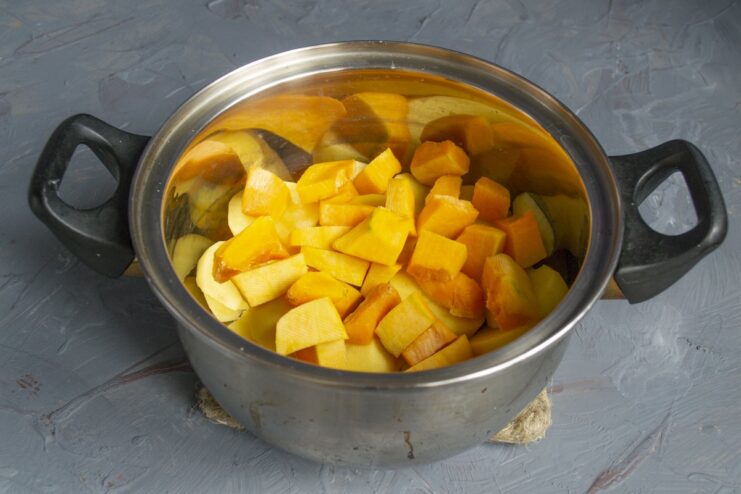 Step 2: Boiling potatoes and pumpkin together Sliced potatoes and chopped pumpkin in a pot with water, ready to be boiled.
