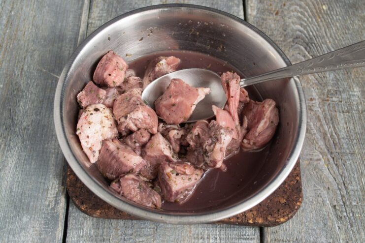 How to Marinate Pork for a Flavorful Stew Raw pork cubes in a bowl, being marinated with spices and red wine before cooking the stew.