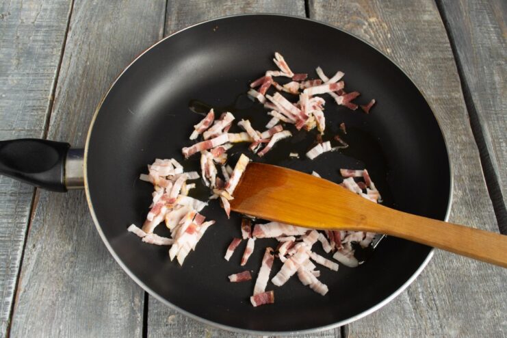 Frying Bacon to Build a Flavor Base for the Stew Strips of smoked bacon being fried in a pan until crispy.