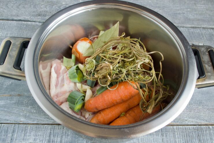 Flavoring the Broth with Carrots and Spices Carrots, bay leaves, and peppercorns added to the pot for the chicken broth.