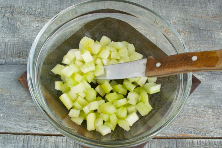 How to Dice Celery for Soup Fresh celery stalks being diced into small cubes on a cutting board.