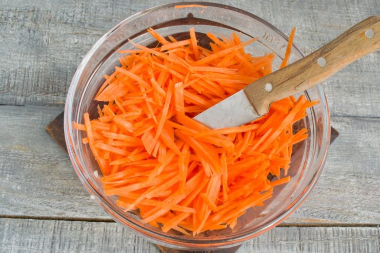 Julienning Carrots for a Perfect Soup Texture Carrots being cut into thin strips (julienned) on a cutting board.