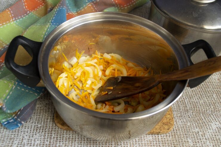 Cooking carrots with onions and garlic until softened. Grated carrots added to the pot with sautéed onions and garlic.
