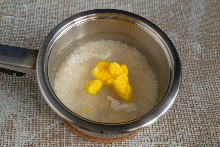 Starting the Plov: Preparing the Saffron Rice with Ghee A pot with jasmine rice, water, and a piece of ghee, the first step for cooking the plov rice.