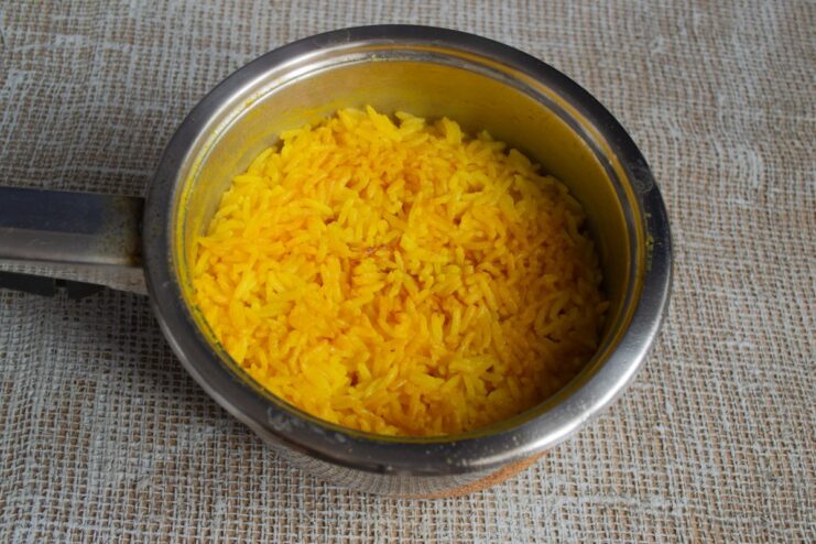 Cooking the Rice to Perfection for a Fluffy Plov A pot of rice simmering on the stove, covered with a lid, to be used in the plov.
