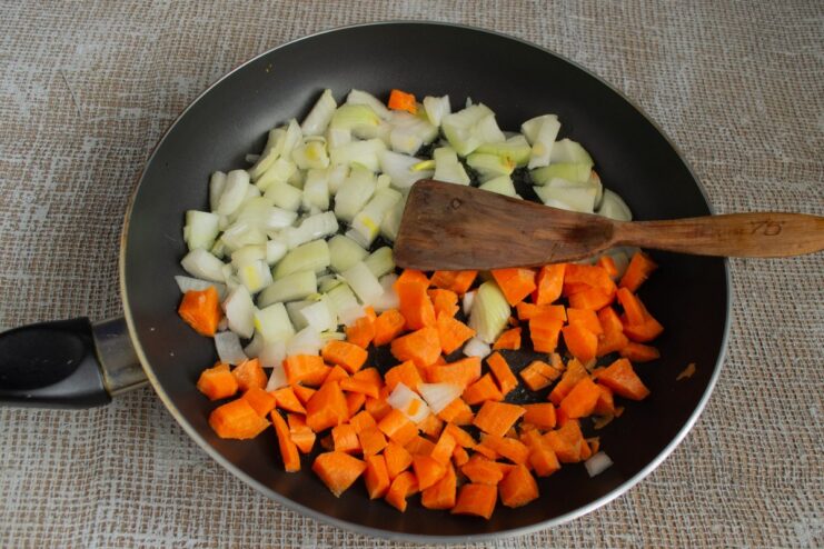 Creating the Flavor Base: Sautéing Onions and Carrots Diced onions and carrots being sautéed in a pan until soft and golden.