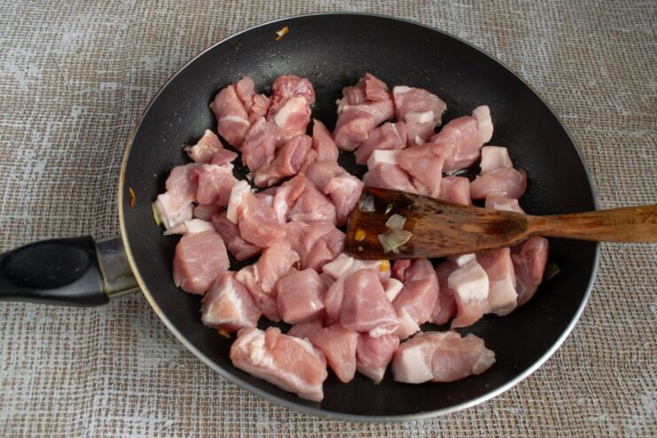 Searing the Meat with Aromatic Spices for the Plov Cubed meat and spices like barberries and cumin being added to a hot pan.