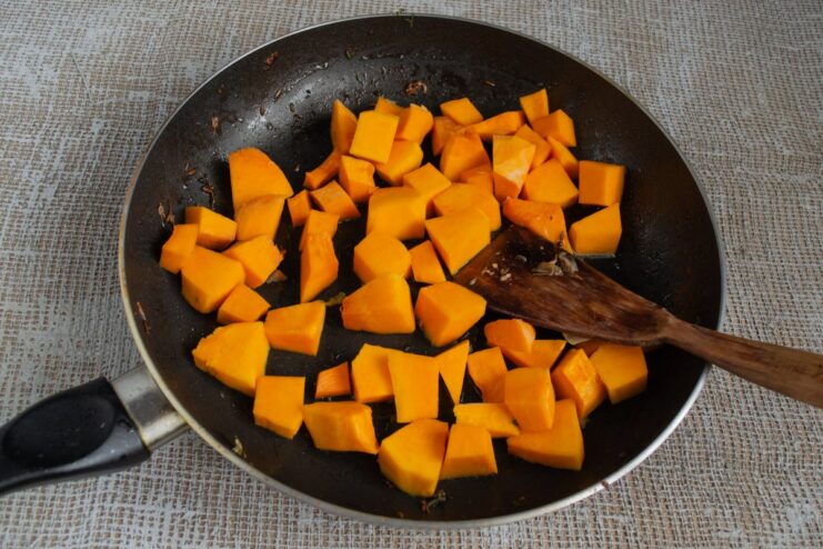 Caramelizing the Pumpkin for a Touch of Sweetness Cubes of pumpkin being fried in a pan until golden, seasoned with salt and sugar.