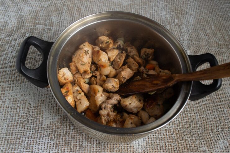 Adding the Savory Meat Layer to the Plov Pieces of fried meat being layered on top of the vegetables in the pot.
