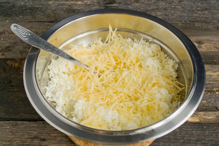 Adding Flavor: Grated Hard Cheese for the Ravioli Filling Grated hard cheese being added to a bowl with tvorog for the ravioli filling.